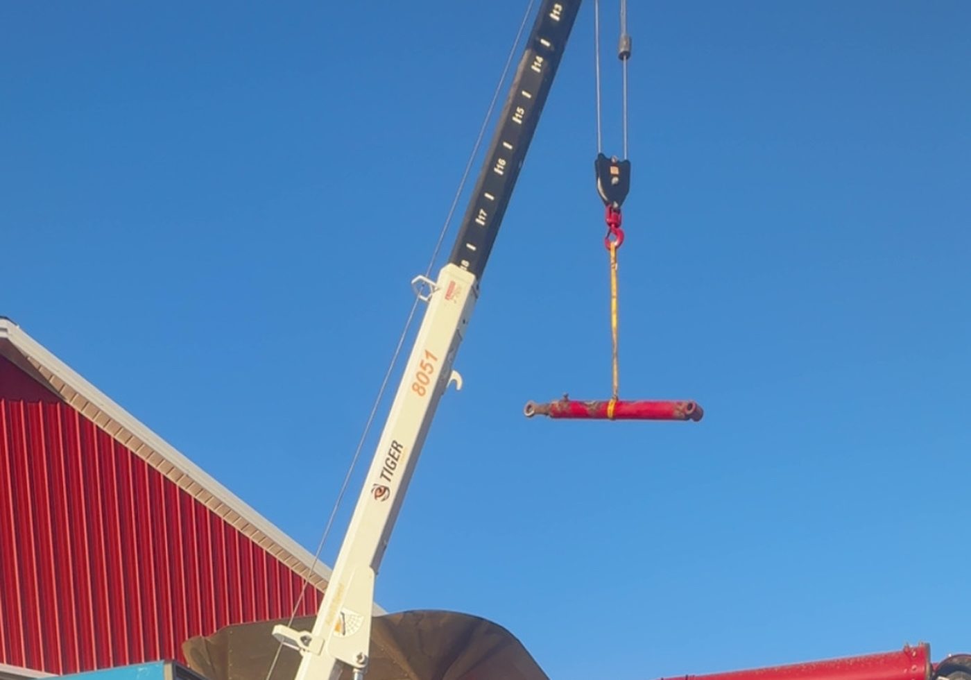 Red Ridge Repair crane lifting a hydraulic cylinder off a combine for on-site repair